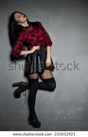 Young beautiful woman wearing black leather skirt, stockings and grille shirt