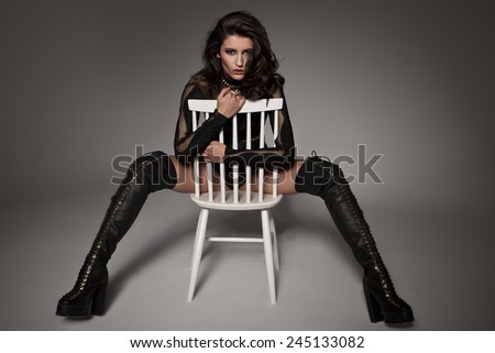 Beautiful brunette model posing on chair in high heel platform boots