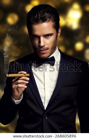 Handsome man with cuban cigar on the golden backgrounde
