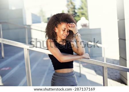 Portrait of a beautiful natural young African woman with afro smiling happiness. Outdoor portrait in sun