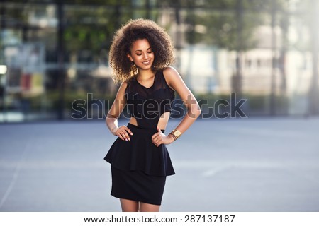 Portrait of a beautiful natural young African woman with afro smiling happiness. Outdoor portrait in sun