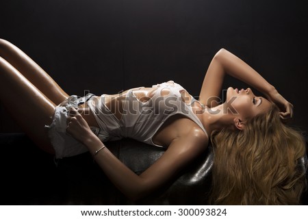 Portrait of young sensual blonde woman in a white wet torn top