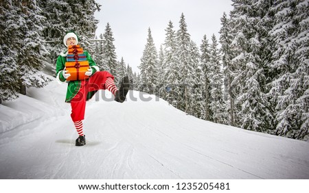 Christmas time and green young elf on winter road with snow