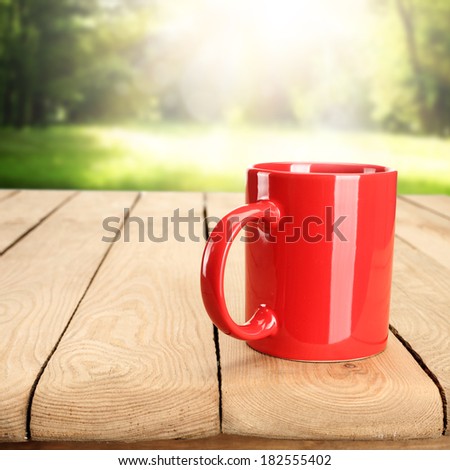 single red mug on wooden retro table and summer space of sun