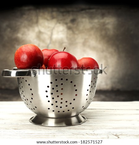 red apples and metal pot on white desk