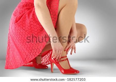 sexy legs of woman in red skirt on gray background