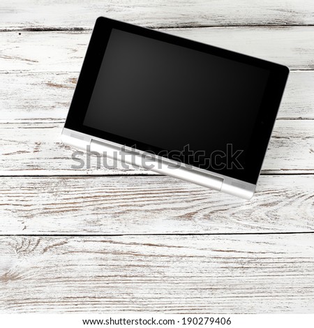 black tablet with silver metal and desk of wood