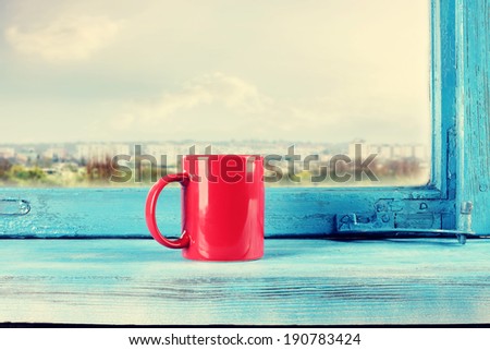 red mug and blue window