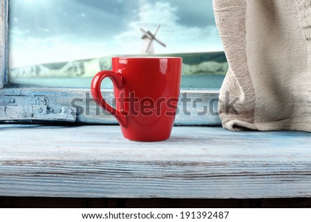 red mug and blue sill with cliffs landscape