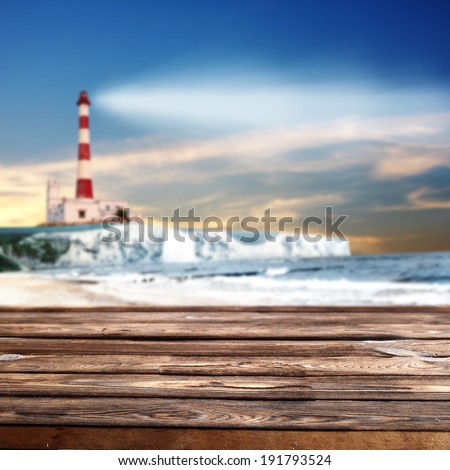 dark night with lighthouse and dark table of wood