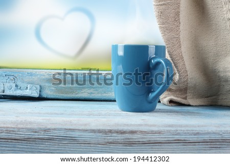 blue mug of coffee and heart on glass