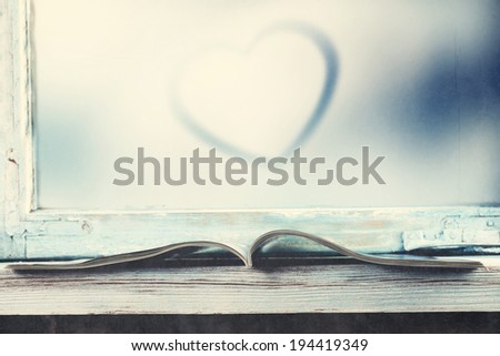 vintage photo of window sill with book heart and glass