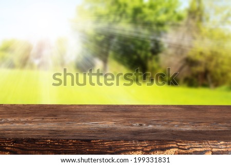 brown wooden desk and green space of summer landscape