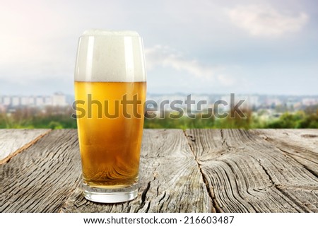 wooden desk of retro chic and glass of beer with landscape of town