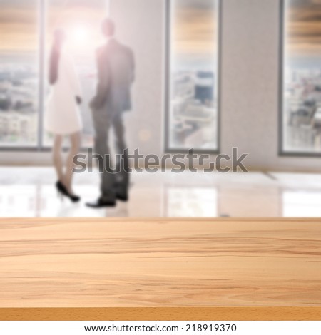 wooden yellow top of desk and two people in office and window with city space