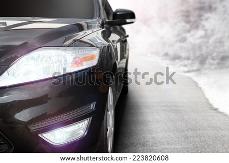 black car without a trade brand and gray road with landscape of snow