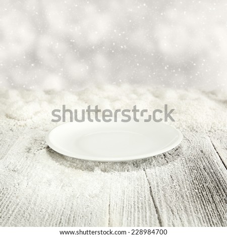 winter background of wooden table of snow and plate