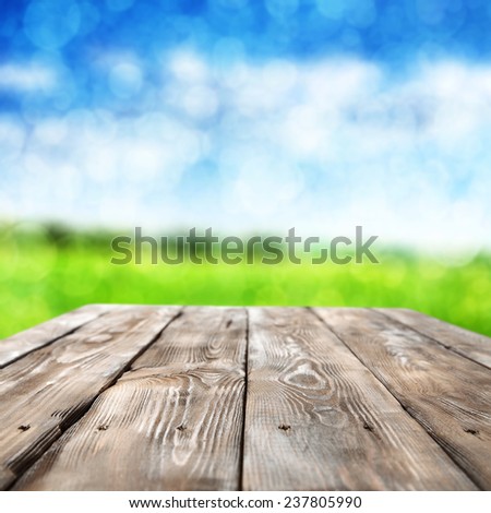 spring landscape of sky and green grass and dark worn table