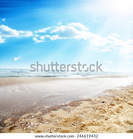landscape of ocean and sun on sky with beach and sand