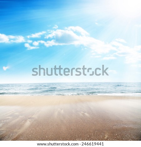 landscape of ocean and sun on sky with wet sand on the beach