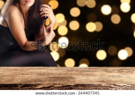 woman in black dress with glass of red wine and brown desk and night