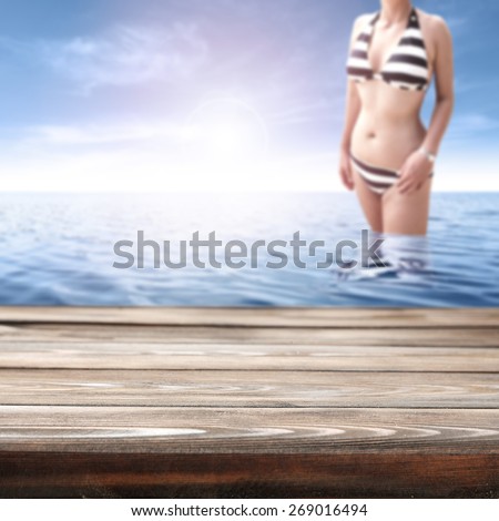woman in bikini in blue water and brown old desk of wood