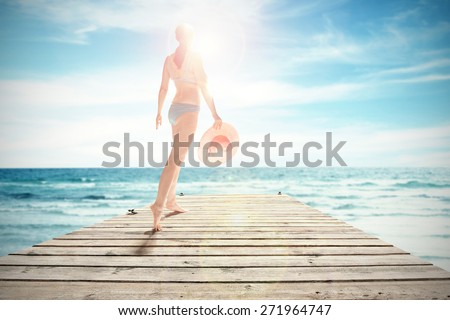 woman on wooden pier on sea and hat of pink color in hand