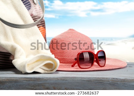 pink hat and red sunglasses on blue desk with bag of summer time