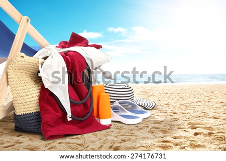landscape of ocean and beach with red towel and bag and shoes