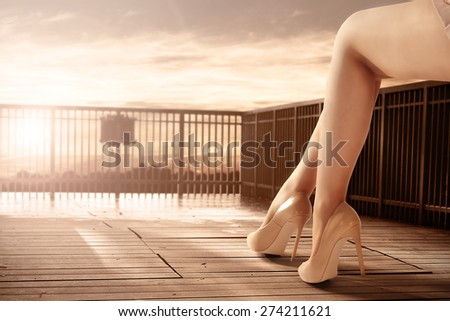 woman legs on terrace and sunset