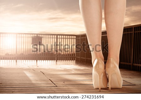 wooden floor of terrace with sunset of summer time and legs of woman on heels