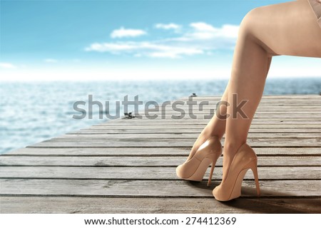 woman legs heels and wooden pier with blue sea and sky