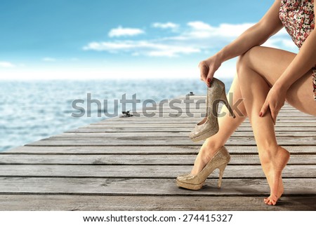 summer landscape of sea and wooden old pier and woman legs