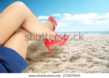 red shoes and legs of woman on sand