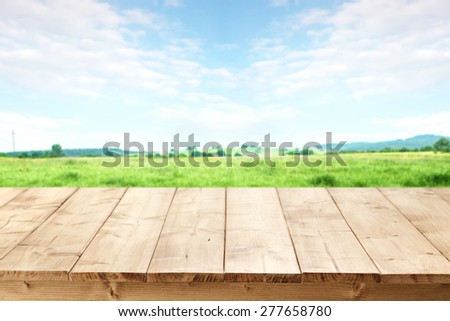 landscape of grass and sky of blue color with free space on table of wood
