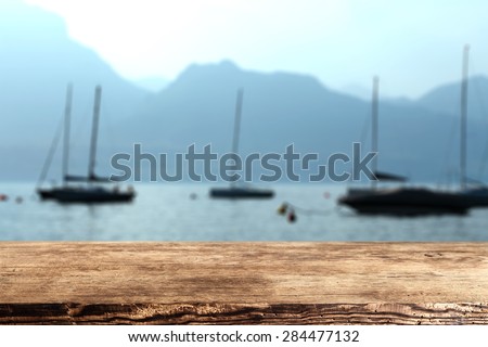 blue landscape of sea and boats and dark brown desk of wood