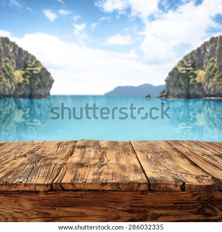 blue water of ocean with landscape of coast and dirty table place of wood