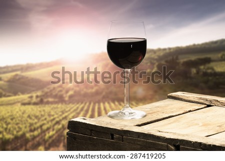 sunset with landscape of tuscany and single glass of red wine