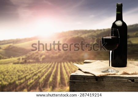 sunset with landscape of tuscany and bottle of red wine