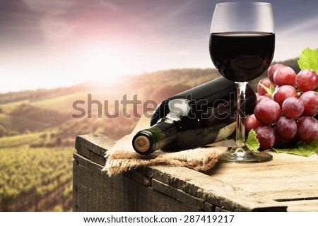 sunset with landscape of tuscany and red wine grapes and bottle