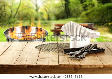 decoration of white cook hat on wooden table and fire in grill