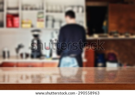 blurred background of interior in bar with barista and dark brown desk space