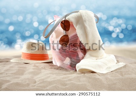hat on sand towel and bag