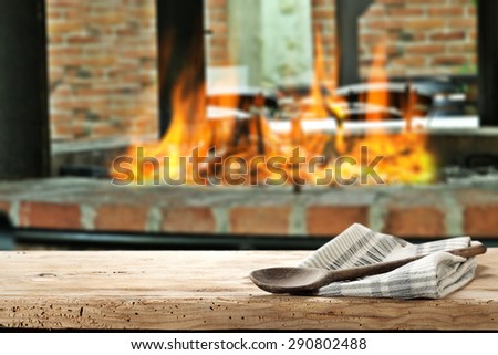 closeup of grill with fire and one wooden spoon on napkin and desk space