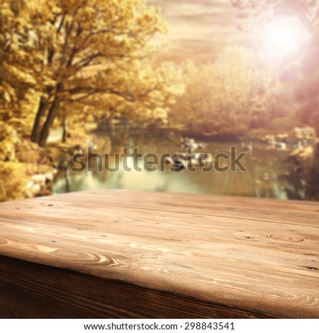 empty desk space of wood and lake of green dark water in autumn forest