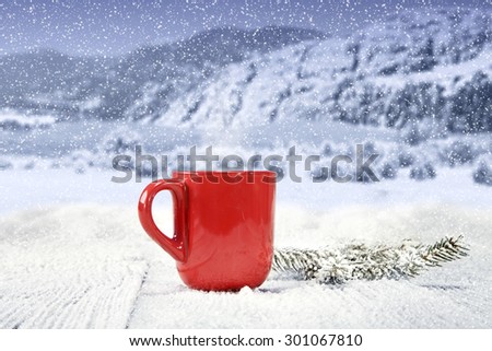 big red mug on wooden table of snow and sky of blue