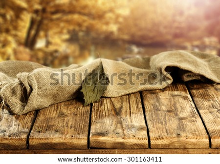 blurred background of autumn park with old trees and table to display