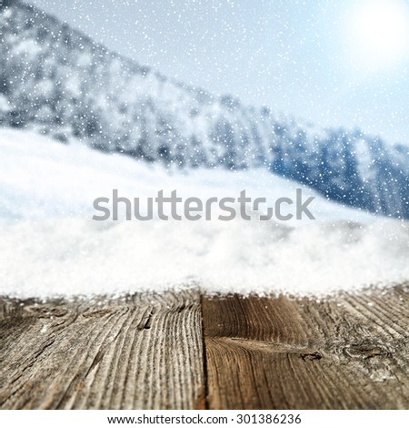 gray wooden table snow decoration and blurred background of mountains