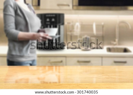 yellow wooden desk top and woman in kitchen with black coffee machine