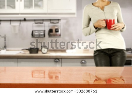 gray blurred background of kitchen with young woman with red mug and  board of red color of wood
